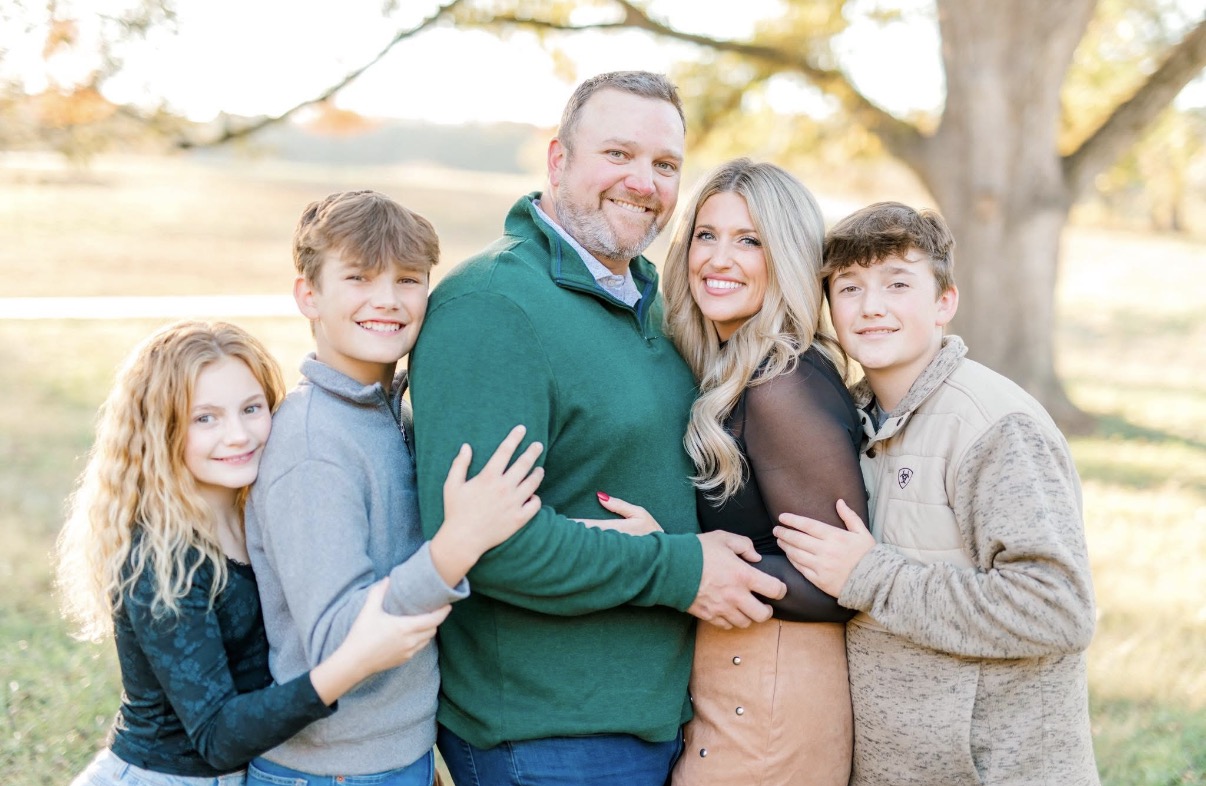 The Boone family standing together on a tree-lined autumn path